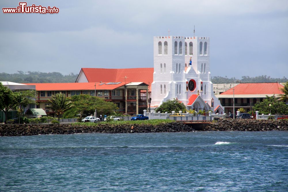 Immagine L'acqua azzurra del mare nella baia su cui si affaccia Apia, Samoa. Sullo sfondo, la facciata bianca di una chiesa cittadina.