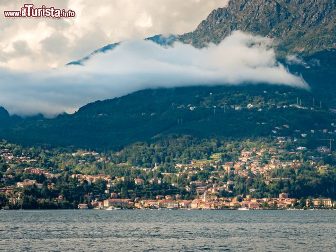 Immagine Lago di Como e Loveno sopra Menaggio, Lombardia. Frazione di Menaggio, Loveno ospita sul suo territorio alcune ville d'epoca di grande prestigio fra cui Villa Mylius Vigoni, sede di un'associazione culturale italo tedesca, e la chiesa di san Lorenzo e Santa Agnese. Questa bella immagine ritrae il centro abitato e il lago di Como sotto una distesa di nuvole - © gnoparus / Shutterstock.com