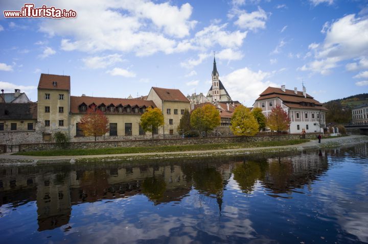 Immagine Le storiche case di Cesky Krumlov, Repubblica Ceca, si specchiano nel fiume - le abitazioni di Cesky Krumlov sono tanto caratteristiche da essere famose in tutta la nazione per i loro colori, l'architettura tipica, per il loro sembrare a tratti delle vere e proprie case delle bambole, con un fascino senza tempo. Tra questi caratteristici tetti, naturalmente, non può che svettare la torre gotica della Chiesa di San Vito. - © gary yim / Shutterstock.com