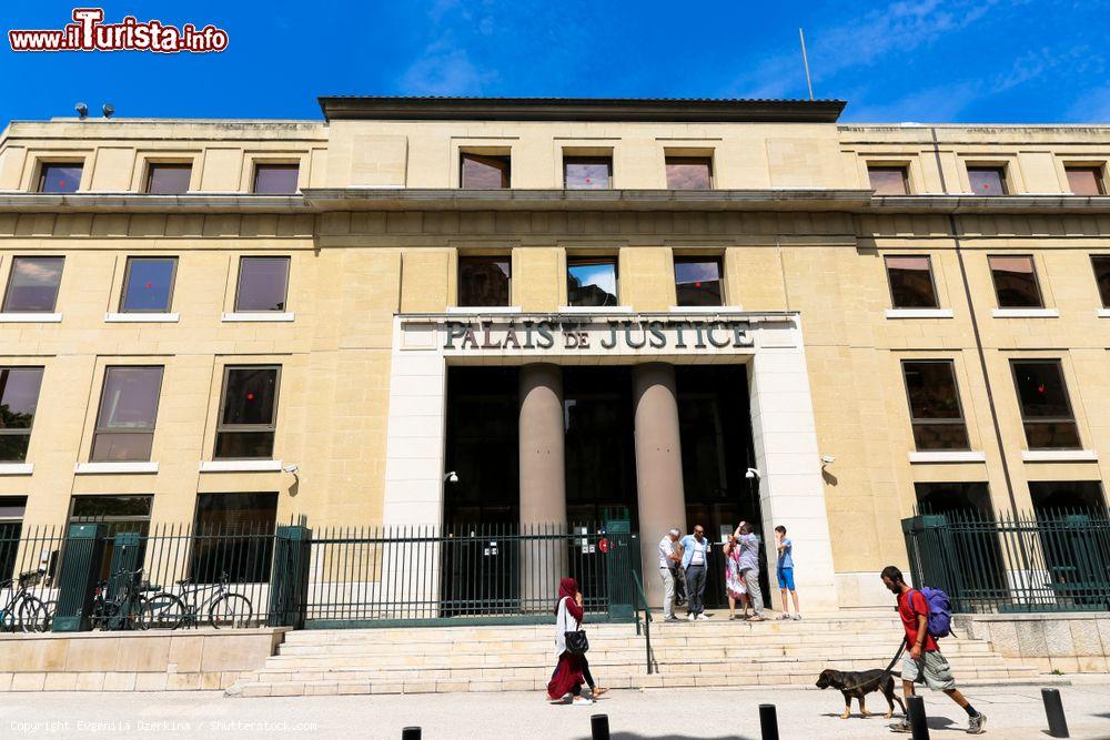 Immagine L'edificio che ospita il Palazzo di Giustizia a Nimes, Francia: una donna araba e un ragazzo con il cane passeggiano davanti al palazzo - © Evgeniia Ozerkina / Shutterstock.com