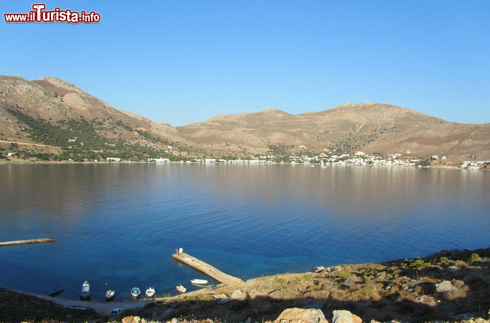 Immagine Livadhia, porto e maggiore città dell'isola di Tilos, Grecia. Questa bella località si trova all'interno di una baia orlata da una spiaggia di ciottoli bianchi.