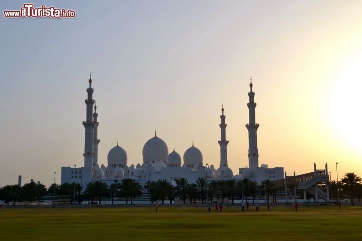 Immagine La vista della Grande Moschea di Abu Dhabi al tramonto è uno di quegli spettacoli che tutti dovrebbero vedere almeno una volta nella vita. La sua sagoma si staglia contro il cielo infuocato e regala emozioni suggestive, come in una favola.
