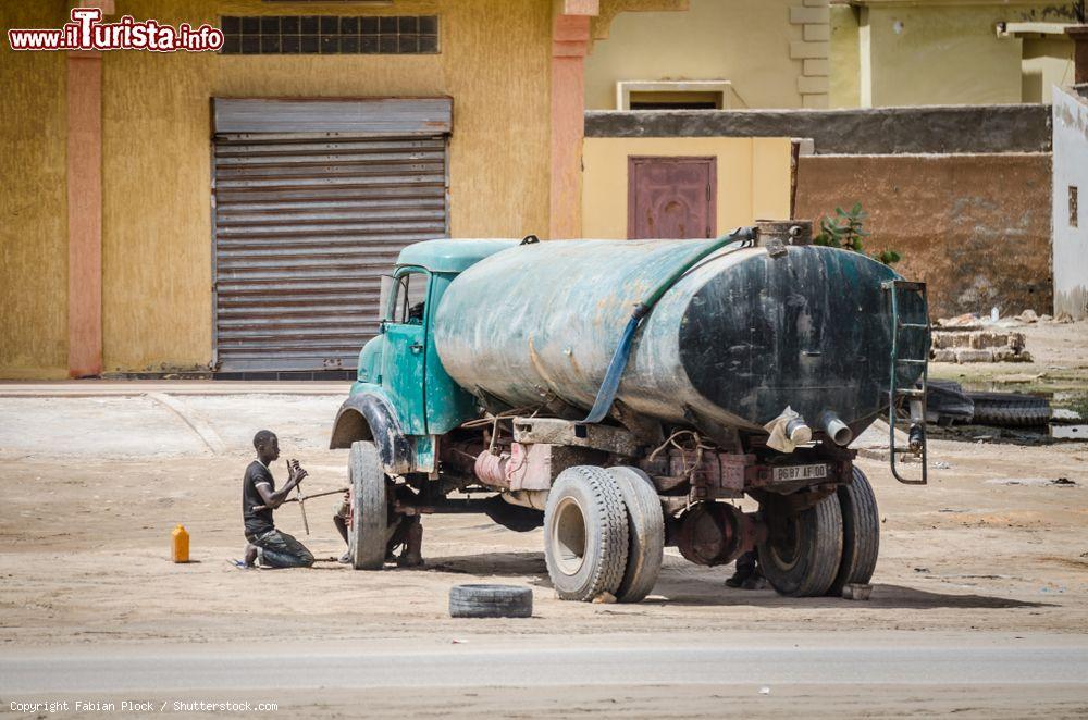 Immagine Nouakchott (Mauritania): due uomini cambiano uno pneumatico a un vecchio camion dell'acqua in una strada della città - © Fabian Plock / Shutterstock.com