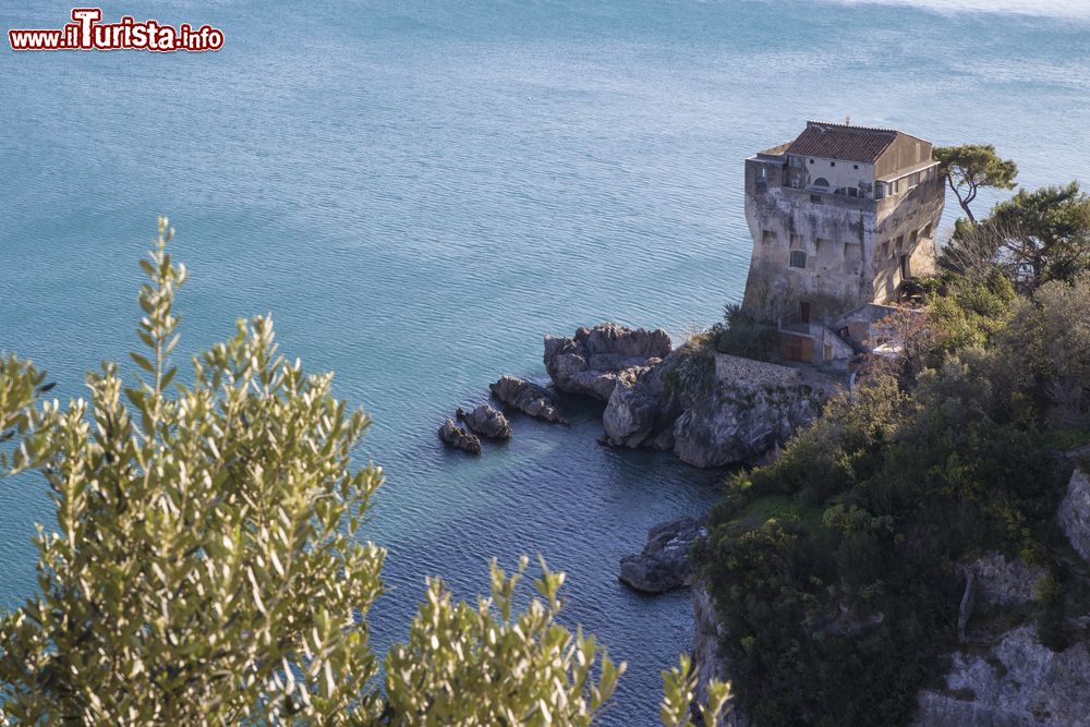 Immagine Torre Crestarella, antica costruzione di Vietri sul Mare, Campania. Impiantata su un grande scoglio poco al di sopra del mare, fu costruita verso la metà del XVI° secolo in seguito all'editto di don Parfan de Ribera a protezione dagli attacchi dei saraceni. In questa immagine è ritratta in una bella giornata soleggiata con il mare blu e la vegetazione rigogliosa.