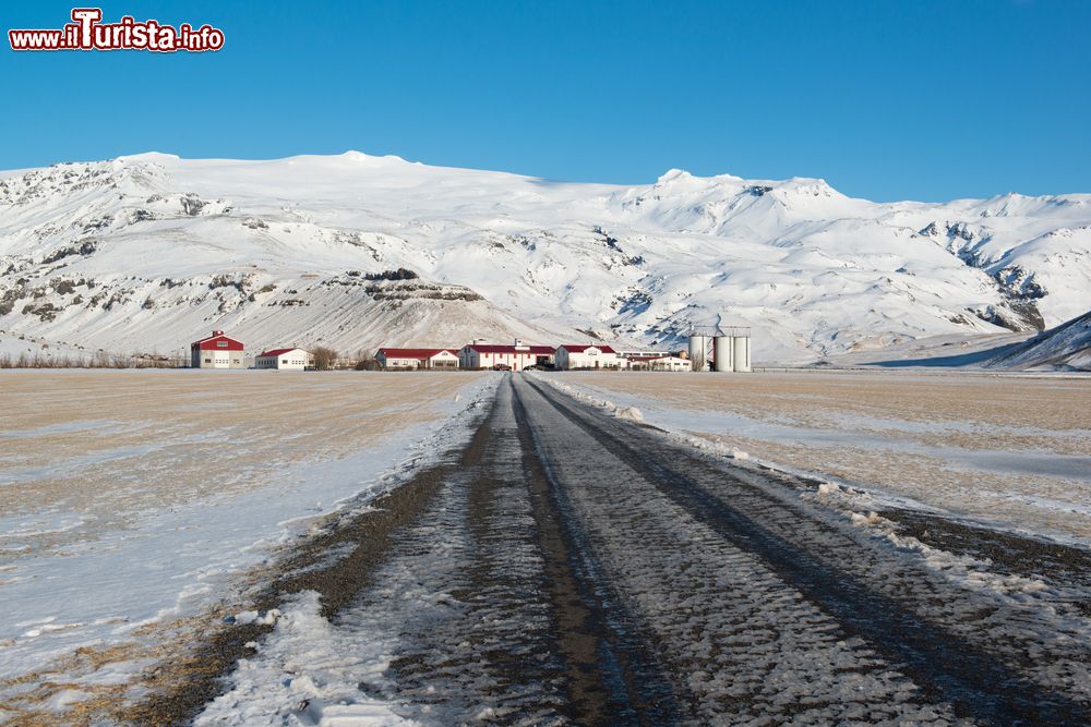 Immagine Paesaggio invernale con azienda agricola sotto il vulcano Eyjafjallajokull, Islanda. Con i suoi 78 chilometri quadrati, è il quinto ghiacciaio islandese per estensione.
