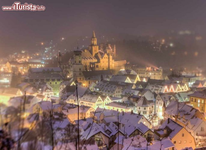 Immagine Panorama del castello di Hohenzollern a Sigmaringen, Germania - Avvolto dalle luci della sera, il castello medievale della città è l'incantevole sfondo per questa immagine scatatta in inverno con i tetti delle case ricoperti da uno strato di soffice neve © Jens Ottoson / Shutterstock.com