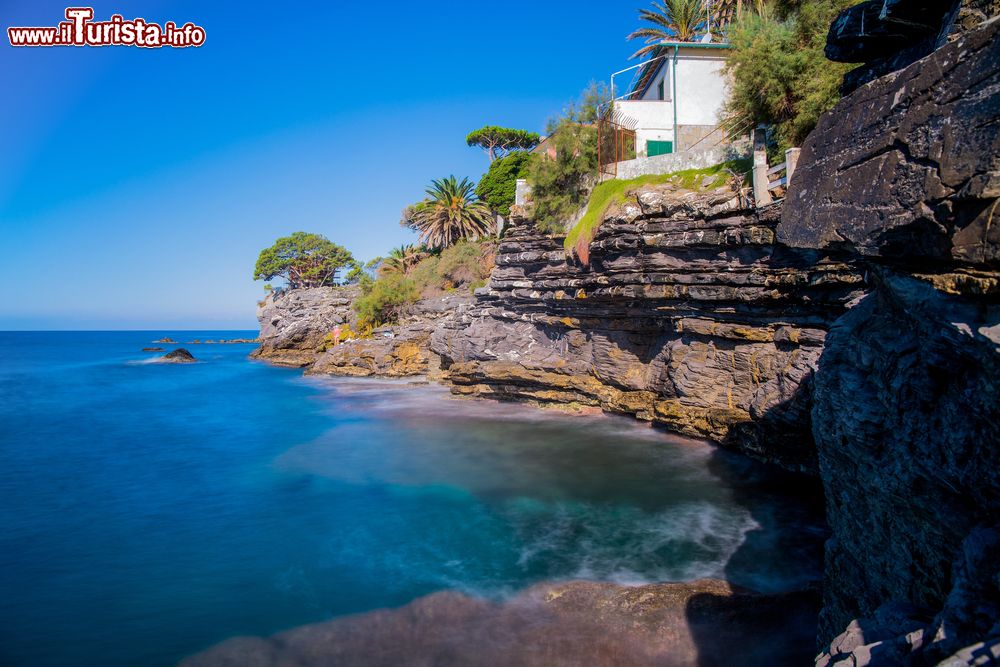 Immagine Panorama di Recco in una splendida giornata estiva con mare e cielo blu, Liguria, Italia. Un suggestivo tratto di costa di questo paese in provincia di Genova: la casa adagiata sulla scogliera è immersa nella vegetazione.