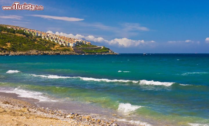 Immagine Panorama su spiaggia e colline a Kusadasi, Turchia - Situata in mezzo a splendidi paesaggi costieri e a importanti siti archeologici, fra cui Mileto, Priene e Didyma, Kusadasi, un tempo piccolo villaggio di pescatori, è oggi una cittadina dedita al turismo. Grazie alla sua vicinanza con le rovine di Efeso, è base ideale anche per le navi da crociera che fanno spola nel mar Egeo © Alex Khripunov / Shutterstock.com