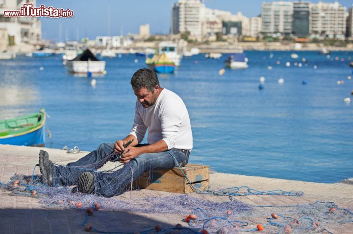 Immagine Un pescatore mentre rammenda le sue reti. La scena è stata ripresa sull'Isola di Malta, a nord-est de La Valletta, più precisamente sulla marina di St Julian's - © Allard One / Shutterstock.com