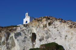 Kimolos (arcipelago delle Cicladi, Grecia sud-orientale): una chiesetta bianca contrasta col blu del cielo e la roccia nuda sopra il porto di Psathì. Il porto è a un chilometro ...