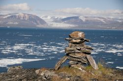 Antichissimo inukshuk dei nativi Inuit, con panorama su di un fiordo dell'Isola di Baffin nel canada settentrionale: è una delle isole più vaste del mondo, la 5a per la precisione ...