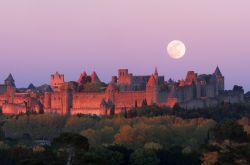Tramonto a Carcassonne (Francia del Sud) con la luna piena che occhieggia alla spalle del borgo. Mentre il sole si congeda le pietre delle mura, costruite a partire dall'età romana ...