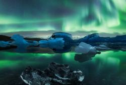 Aurora boreale al Jokulsarlon Glacier Lagoon, Islanda. Questa laguna di origine glaciale fluisce nell'Oceano Atlantico attraverso un breve canale lasciando blocchi di ghiaccio su una spiaggia ...