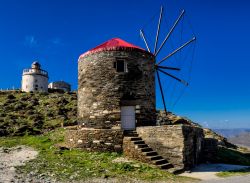 Faro e mulino a vento sull'isola di Tino, Cicladi, Grecia. Questa graziosa isola è caratterizzata da retaggi veneziani, buona cucina e mare cristallino.

