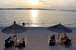 Gente in relax al tramonto sulla spiaggia di Fazana, di fronte alle isole Brioni, Croazia - © Dino Geromella / Shutterstock.com