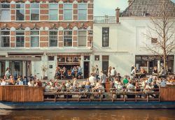 Gente pranza su una barca-caffé all'aperto lungo i canali di Den Haag, Olanda - © Radiokafka / Shutterstock.com