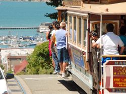 Gente sul tram a funivia a San Francisco, California (USA). Questo sistema di trasporto a funivia è l'ultimo azionato manualmente in tutto il mondo - © Vacclav / Shutterstock.com ...