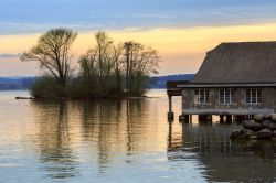 Il lago di Zugo visto al tramonto in primavera, Svizzera. Una pittoresca casa residenziale costruita sull'acqua.

