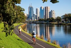 In bici sulla ciclabile lungo il fiume Yarra a Melbourne, Victoria, Australia. Sullo sfondo, la skyline della città, la seconda più popolosa del paese dopo Sidney - © Norman ...
