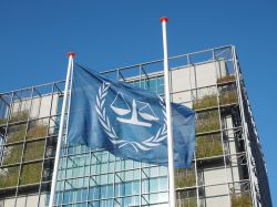 La bandiera e l'edificio principale della Corte Internazionale dei Crimini a L'Aia (Olanda) - © STRINGER Image / Shutterstock.com