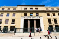 L'edificio che ospita il Palazzo di Giustizia a Nimes, Francia: una donna araba e un ragazzo con il cane passeggiano davanti al palazzo - © Evgeniia Ozerkina / Shutterstock.com