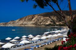 Ombrelloni e sdraio su una spiaggia della baia di Pissouri, Cipro, in una soleggiata mattina estiva.

