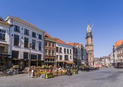 Persone intente a bere un drink in piazza Houtmarkt a Zutphen, Olanda. La giornata soleggiata e la 'Wijnhuistoren' sono la perfetta cornice per una sosta in uno dei locali cittadini ...