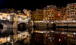 Ponte Vecchio e la magia notturna del centro storico di Firenze che si specchia nel fiume Arno, Toscana.
