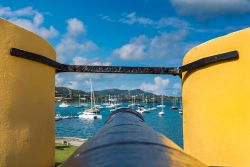 Punta di un cannone d'epoca a Christiansted, isola dei Saint Croix, Stati Uniti. Sullo sfondo, barche a vela e yachts ormeggiati.

