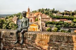 Scultura a Longiano, Emilia Romagna, Italia. Una bella opera scultorea che raffigura un ragazzo seduto sulle mura del borgo medievale - © GoneWithTheWind / Shutterstock.com