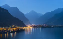 Panorama notturno delle montagne del Canton Uri e il Lago dei Quattro Cantoni in Svizzera. Il villaggio di Fluelen in primo piano