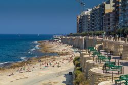 La spiaggia di Exiles, Sliema, fotografata in estate, Malta. Turisti in relax fra bagni in mare e abbronzatura - © TheLiftCreativeServices / Shutterstock.com