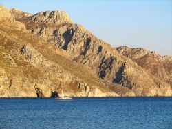 Un tratto della costa di Tilos lambita dalle acque blu del mare, Grecia. Selvaggio e roccioso, questo territorio greco ospita antiche vestigia. 

