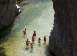 Alcuni turisti affrontano le fresche acque del fiume Alcantara dentro alle gole di basalto - © Natursports / Shutterstock.com