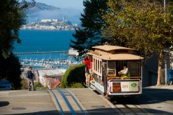 Turisti sul celebre tram a San Francisco, California, in una giornata di sole. Dalla cima di Hyde Street si gode un'impareggiabile vista sulla baia e la prigione di Alcatraz - © Pius ...