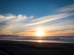 Un suggestivo tramonto a Pichilemu visto da Playa Hermosa, Cile. Le sfumature del cielo si riflettono nell'acqua del mare.
