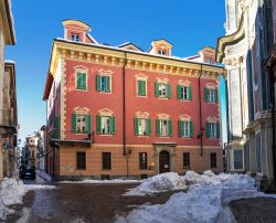 Un tipico edificio dalla facciata colorata su una stradina innevata della città di Cuneo, Piemonte

