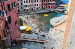 Una bella veduta di Vernazza con gente al mare e nella piazza, La Spezia, Liguria. Questo pittoresco borgo è uno dei siti protetti dall'Unesco nel Parco Nazionale delle Cinque Terre ...