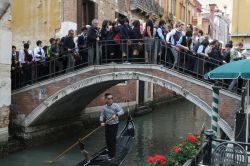 Una fila di turisti su un ponte di Venezia in una giornata da bollino nero- © Bumble Dee / Shutterstock.com