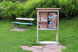 Una piccola libreria all'aperto in un giardino pubblico di Saint-Jean-de-Luz, Francia. Sullo sfondo, una panchina colorata - © Roel Slootweg / Shutterstock.com