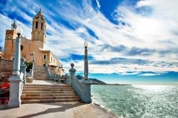 Una suggestiva veduta della chiesa di San Bartolomeo e Santa Tecla a Sitges, Spagna. L'edificio religioso si affaccia sul mare; dalla sua terrazza si gode uno splendido panorama sul litorale ...