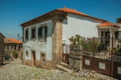 Una tipica casa del centro storico di Linhares da Beira, Portogallo. A fianco, un cancello in ferro e fiori colorati abbelliscono il vicolo ciottolato.

