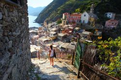 Una giovane donna scende le scale di una viuzza di Vernazza, La Spezia, Liguria. Percorsi ripidi accompagnano alla piazzetta situata in fondo al porticciolo.
