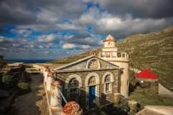 Un'antica chiesetta lungo la strada per la città di Isternia, isola di Tino, Grecia. A fianco, un tradizionale mulino a vento con il tetto rosso.
