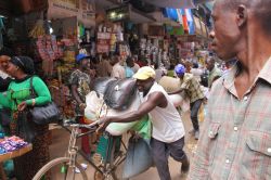 Uomini spingono bici cariche di merci al mercato Kikuubo di Kampala, Uganda. Siamo in uno dei principali mercati cittadini - © Tim Hook / Shutterstock.com