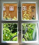 Veduta di un giardino con bicicletta al Fuggerei di Augusta, Germania, attraverso una finestra. Ancora oggi, come un tempo, i cancelli di questo antico complesso vengono chiusi alle 22 - © ...