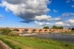 Veduta estiva del ponte ad archi sul fiume Loira a Nevers, Francia, in una giornata di cielo azzurro con le nuvole.

