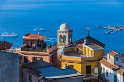 Vista mattutina dai tetti del villaggio di Castelmola, Sicilia. Le prime luci dell'alba illuminano i tetti delle case di Castelmola con sullo sfondo Giardini Naxos e due navi da crociera ...