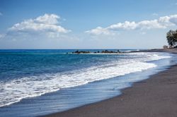 La spiaggia sabbiosa di Vourvoulos sulla costa nord-est dell'isola di Santorini, Grecia. Sabbiosa e appartata, questa spiaggia di sabbia grigia e ciottoli è sovrastata da imponenti ...
