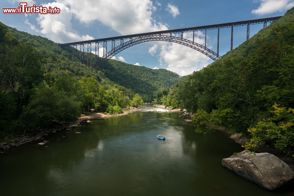 Immagine L'alto ponte ad arco nelle gole del New River, West Virginia. Un gommone con turisti si dirige verso le rapide del fiume.